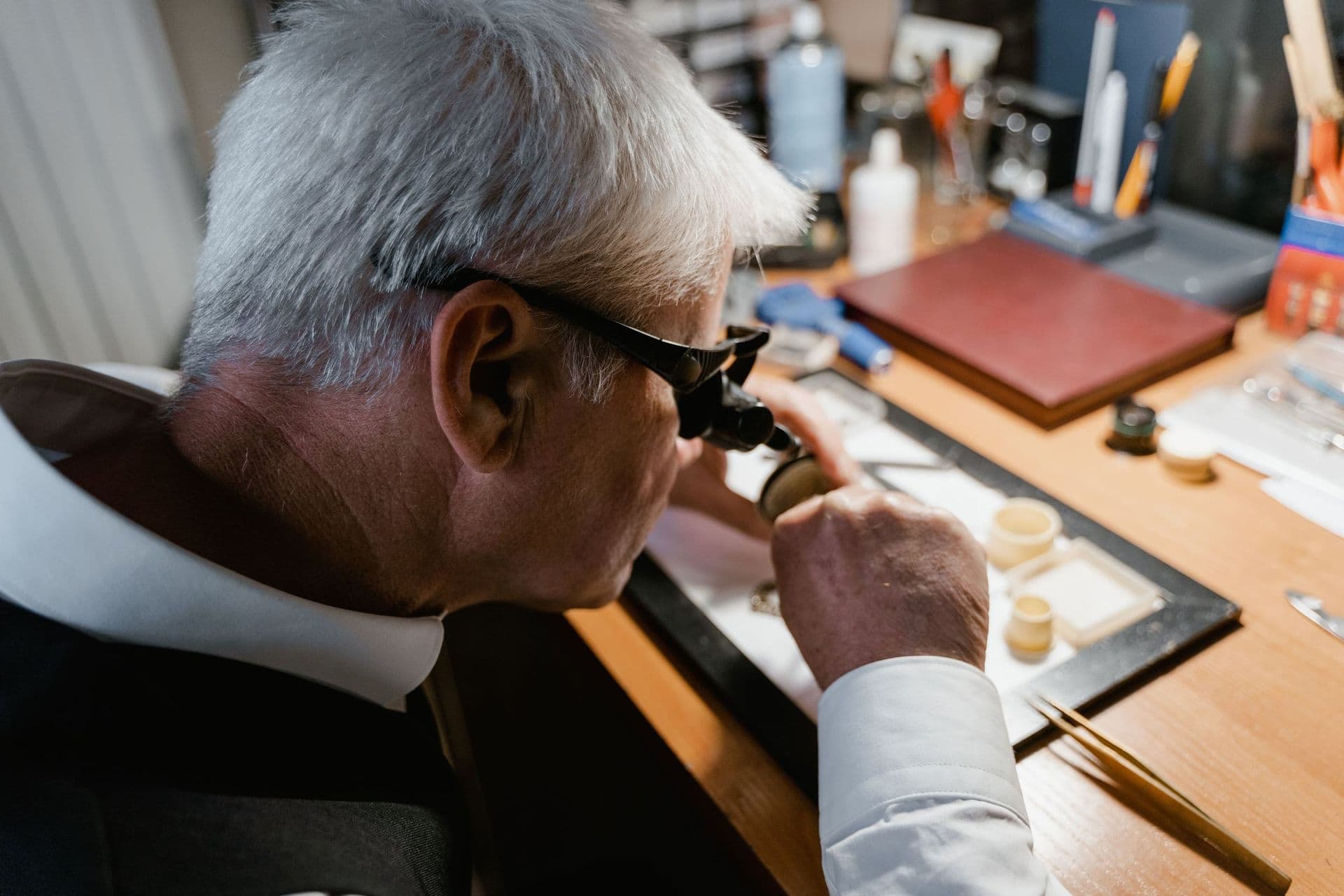A jeweller inspecting a piece through a loupe in the atelier