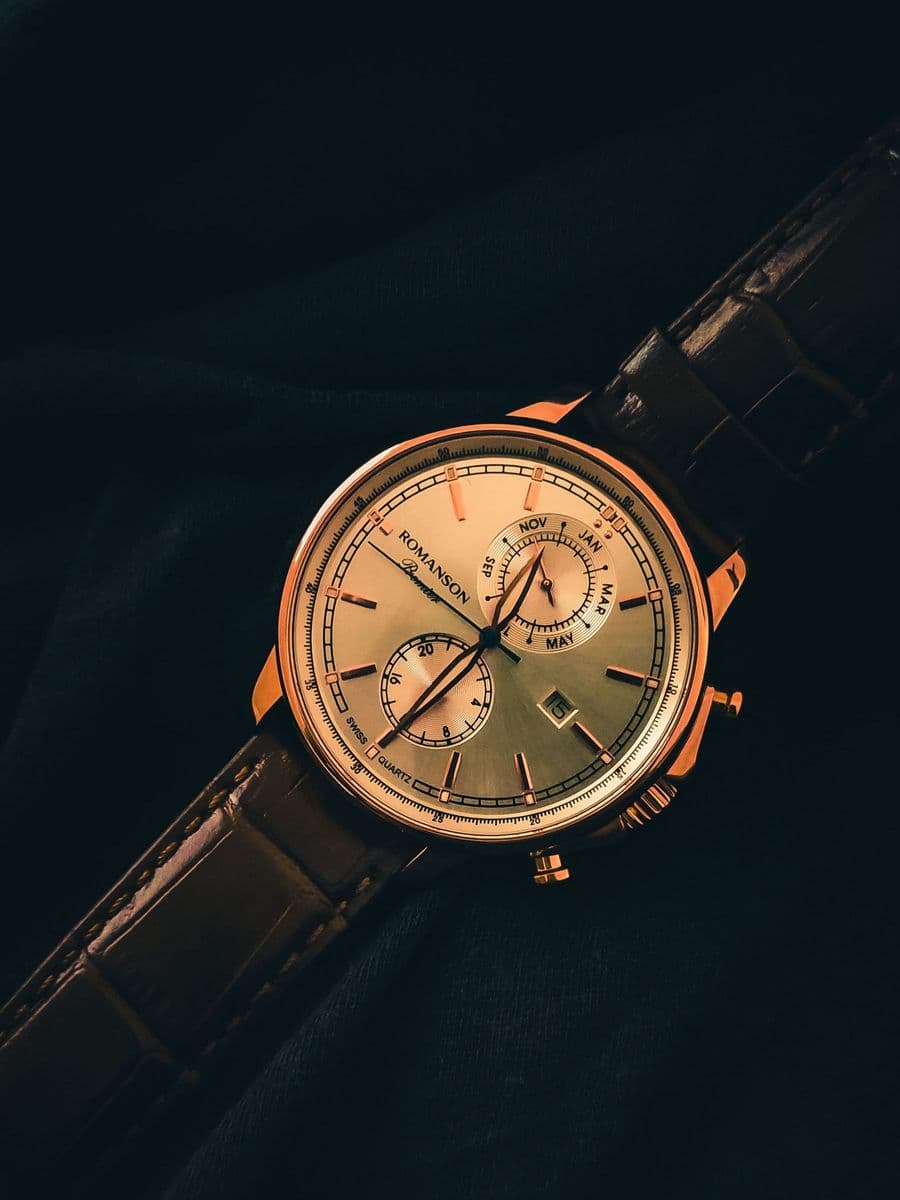 A watch with a champagne dial on a dark background