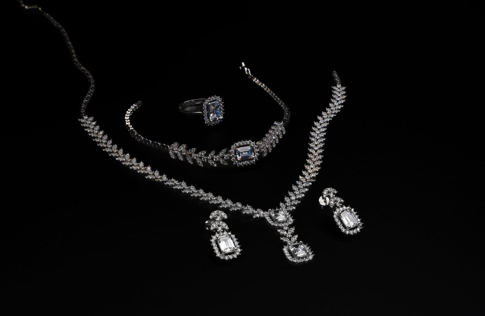 A diamond necklace, ring and earrings on black