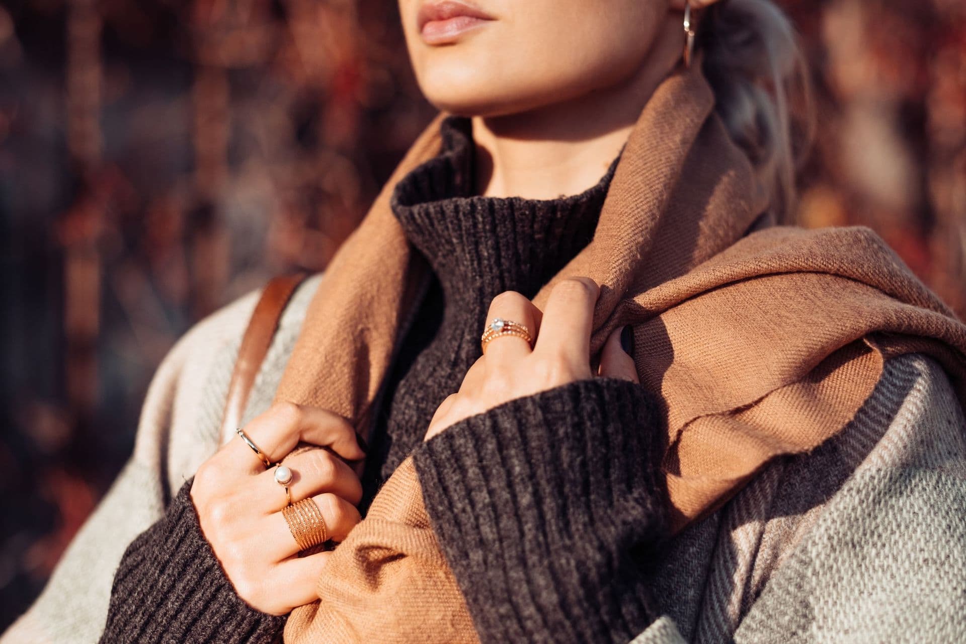 A woman in a sweater wearing gold rings