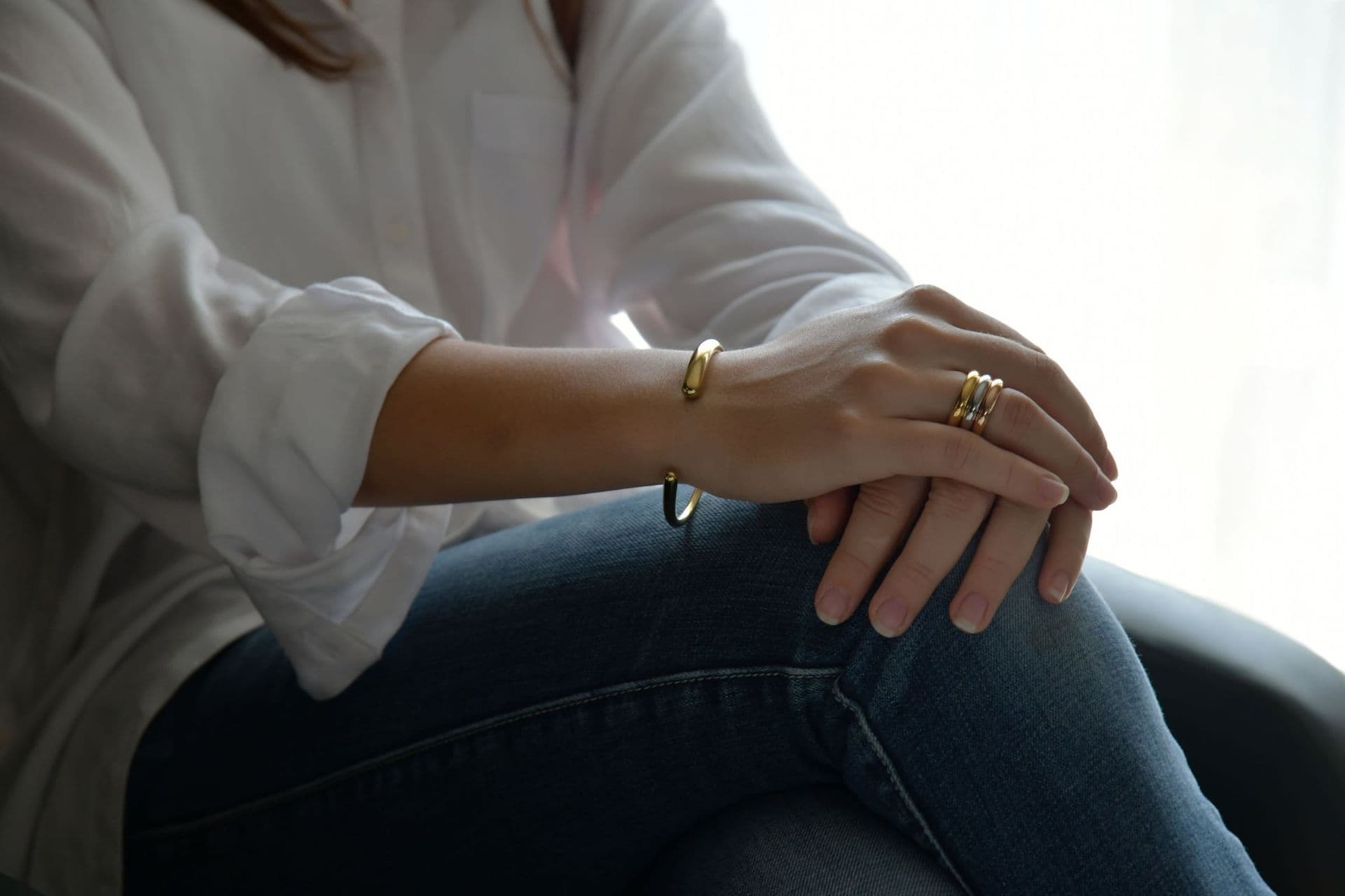 A gold bracelet and rings with a white shirt