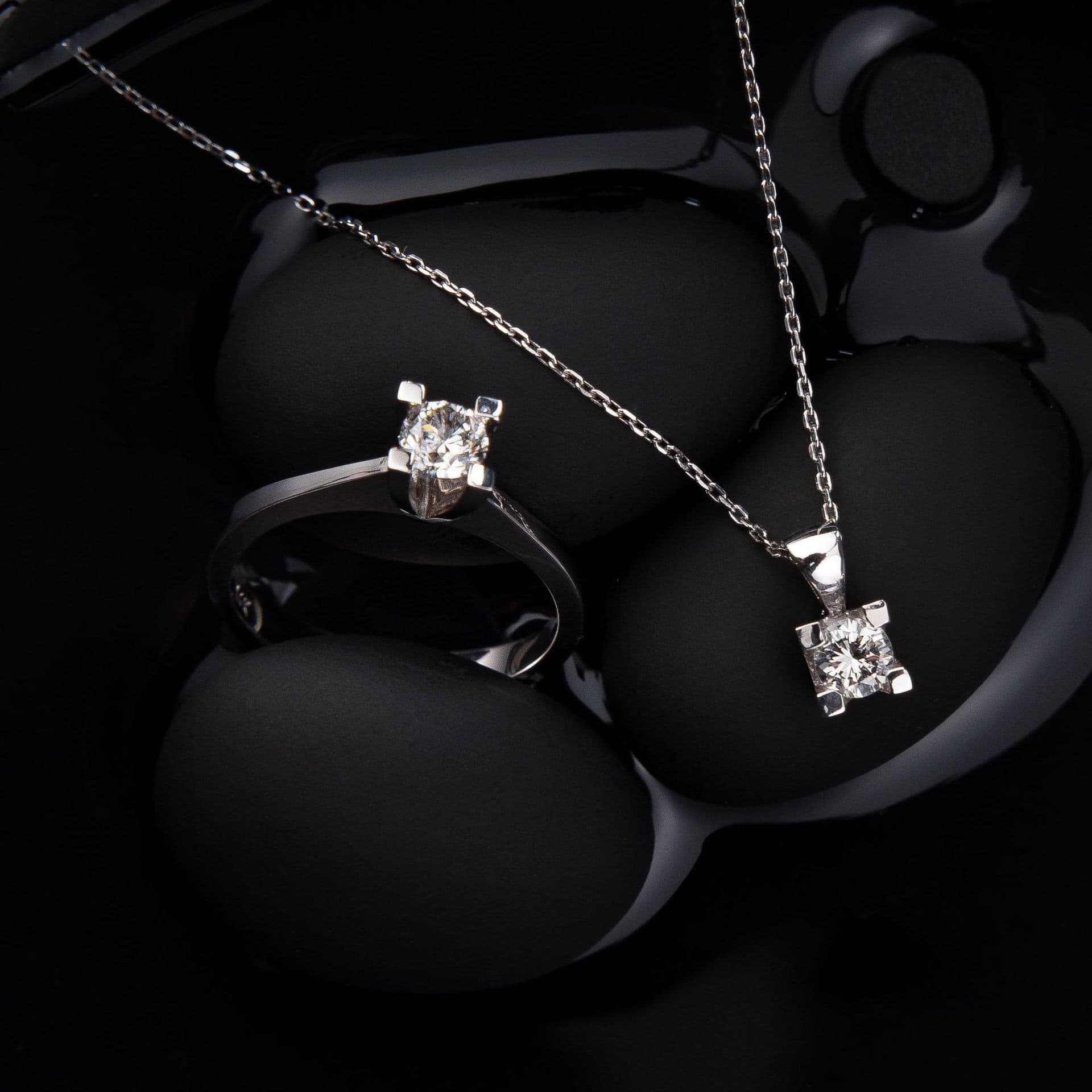 A silver necklace and ring with a square stone